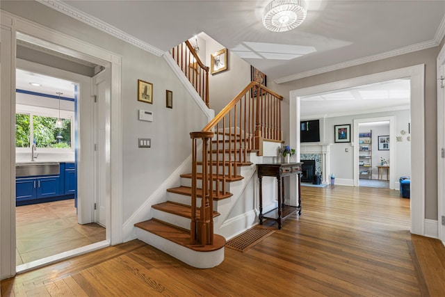 225 Fisher Ave, White Plains, NY 10606 - stairs with wood finished floors, crown molding, a fireplace, and a chandelier