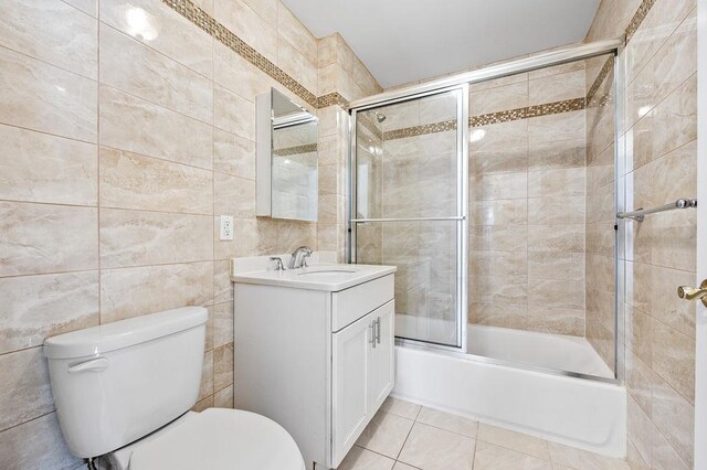 16001 Sanford Ave, Flushing, NY 11358 - full bathroom with toilet, vanity, tile walls, combined bath / shower with glass door, and tile patterned floors