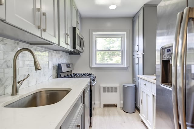 221 Middle Neck Rd Unit M-4, Great Neck, NY 11021 - kitchen featuring stainless steel appliances, backsplash, gray cabinetry, and light wood-style floors