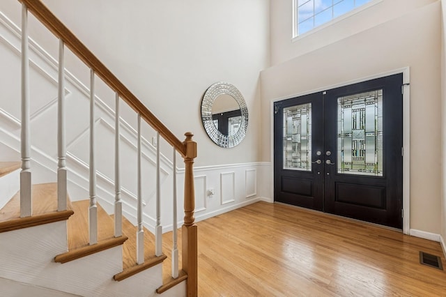 287 Atlantic Ave, Massapequa Park, NY 11762 - entrance foyer with french doors, stairway, light wood finished floors, a high ceiling, and wainscoting