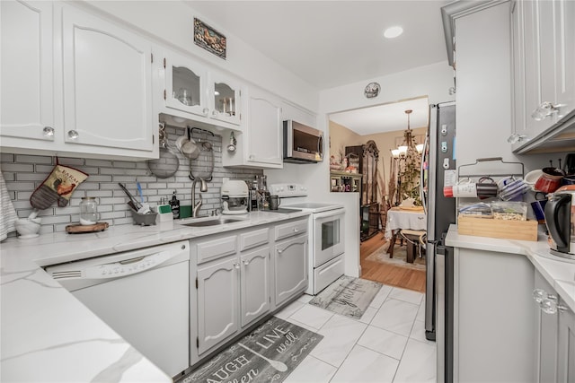 608 Kemeys Cv Unit 6-08, Briarcliff Manor, NY 10562 - kitchen featuring stainless steel appliances, a chandelier, decorative backsplash, a sink, and glass insert cabinets