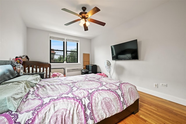 86-04 Grand Ave Unit 4D, Elmhurst, NY 11373 - bedroom featuring wood finished floors, baseboards, a wall mounted AC, and ceiling fan