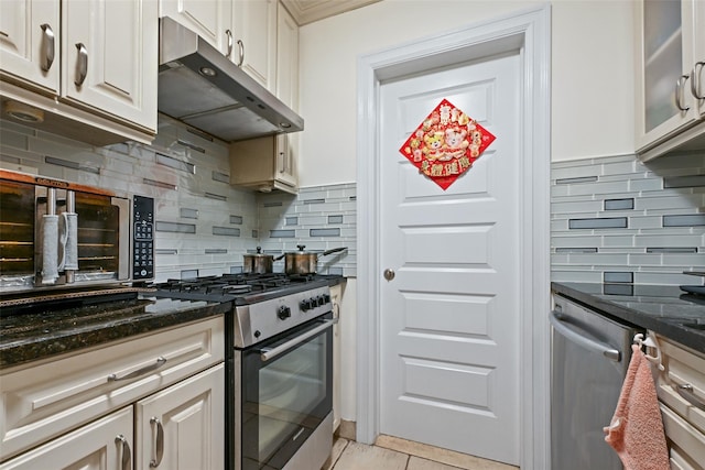86-04 Grand Ave Unit 4D, Elmhurst, NY 11373 - kitchen with appliances with stainless steel finishes, under cabinet range hood, tasteful backsplash, dark stone counters, and glass insert cabinets