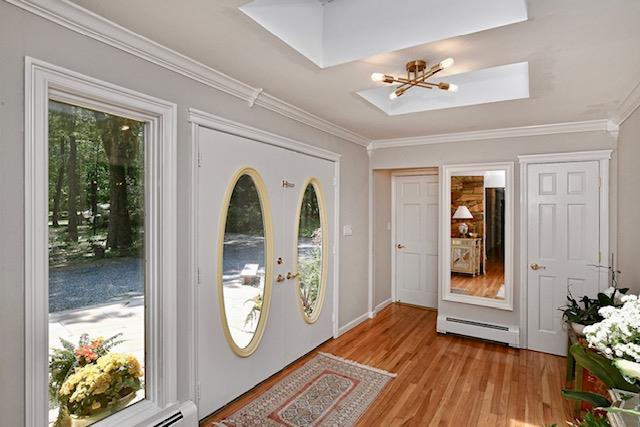 2 Wooded Ct, Lloyd Harbor, NY 11743 - entryway featuring a baseboard heating unit, a chandelier, ornamental molding, light wood-style flooring, and a skylight