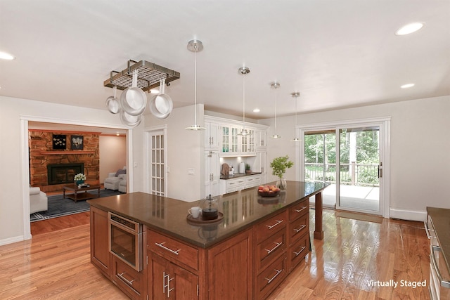 2 Wooded Ct, Lloyd Harbor, NY 11743 - kitchen featuring light wood-type flooring, a center island, brown cabinetry, glass insert cabinets, and decorative light fixtures