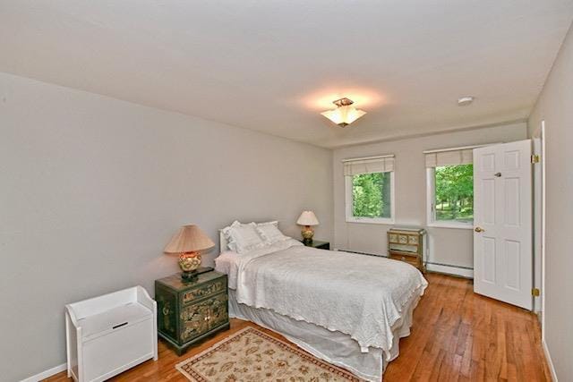 2 Wooded Ct, Lloyd Harbor, NY 11743 - bedroom with a baseboard heating unit, wood finished floors, and baseboards