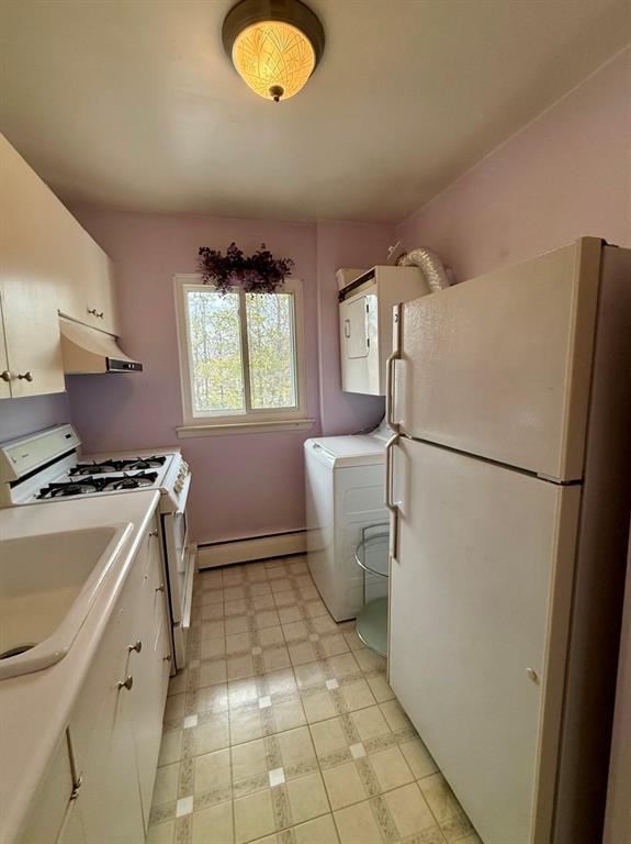 73 Adams Rd Unit 2B, Central Islip, NY 11722 - kitchen featuring white appliances, a baseboard radiator, under cabinet range hood, white cabinetry, and washer / dryer
