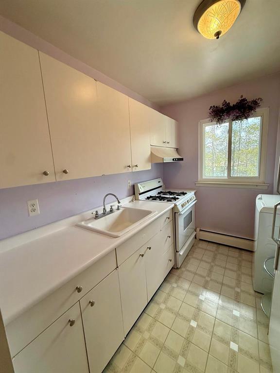 73 Adams Rd Unit 2B, Central Islip, NY 11722 - kitchen featuring white gas range, baseboard heating, under cabinet range hood, a sink, and light countertops