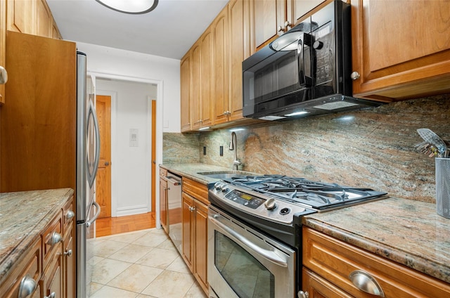 1299 Palmer Ave Unit 332, Larchmont, NY 10538 - kitchen with stainless steel appliances, backsplash, light stone countertops, light tile patterned floors, and brown cabinets