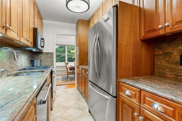 1299 Palmer Ave Unit 332, Larchmont, NY 10538 - kitchen featuring stainless steel appliances, decorative backsplash, brown cabinetry, light tile patterned flooring, and light stone countertops