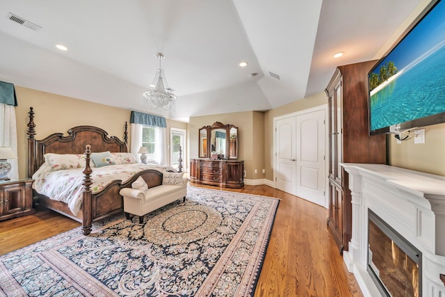 13 Locust Ln, Upper Brookville, NY 11545 - bedroom with light wood-type flooring, a lit fireplace, a chandelier, vaulted ceiling, and recessed lighting
