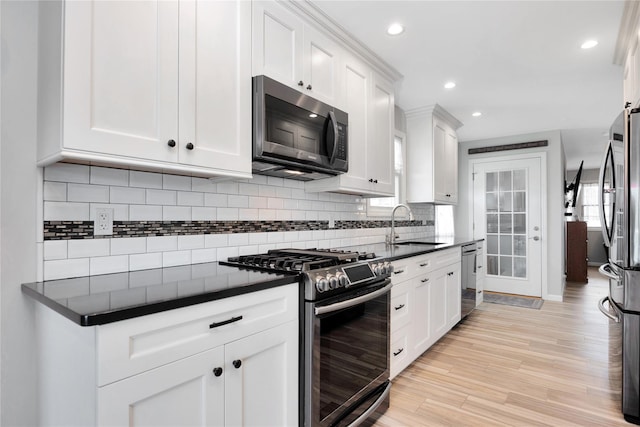 3717 Somerset Dr, Seaford, NY 11783 - kitchen with stainless steel appliances, dark countertops, a sink, white cabinets, and light wood-type flooring
