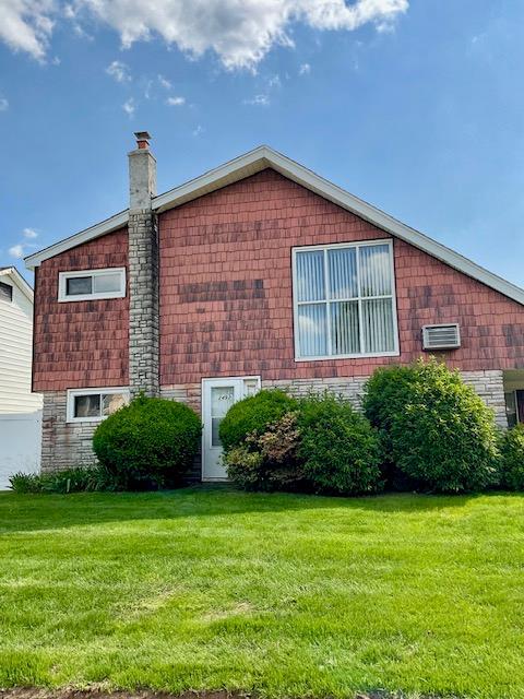2492 2nd St, East Meadow, NY 11554 - view of side of property with a lawn, a chimney, and stone siding