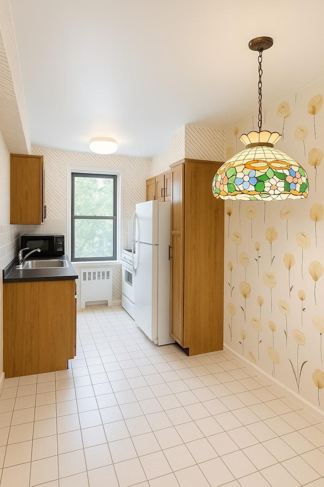 32-23 90th St Unit 103, East Elmhurst, NY 11369 - kitchen featuring freestanding refrigerator, radiator heating unit, brown cabinetry, dark countertops, and decorative light fixtures
