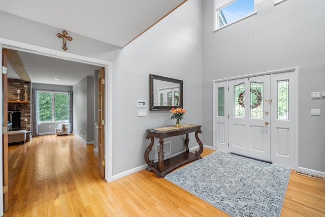 83 Mcdonald Rd, Ossining, NY 10562 - foyer featuring light wood finished floors, a brick fireplace, and a high ceiling