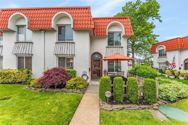 62 Alhambra Dr, Oceanside, NY 11572 - view of front of property featuring mansard roof, a tile roof, stucco siding, and a front lawn