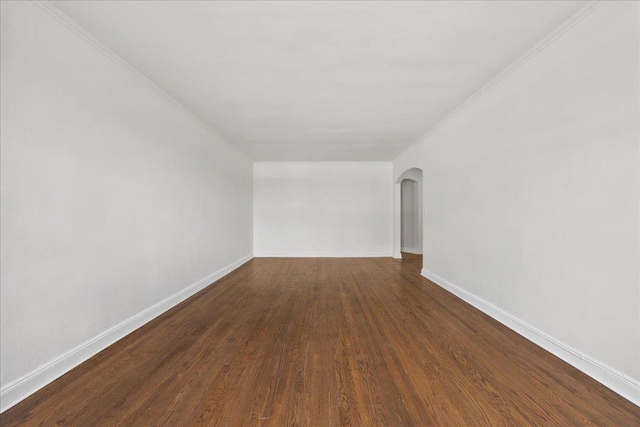 98-120 Queens Blvd Unit 5G, Rego Park, NY 11374 - spare room featuring arched walkways, dark wood-style flooring, baseboards, and ornamental molding