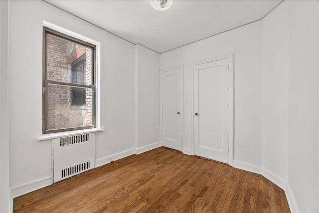 98-120 Queens Blvd Unit 5G, Rego Park, NY 11374 - empty room featuring radiator, wood finished floors, and baseboards