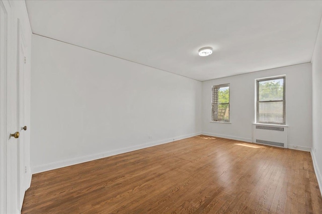98-120 Queens Blvd Unit 5G, Rego Park, NY 11374 - empty room with radiator heating unit, wood finished floors, and baseboards