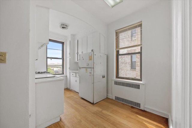98-120 Queens Blvd Unit 5G, Rego Park, NY 11374 - kitchen with freestanding refrigerator, radiator heating unit, light wood-style flooring, light countertops, and white cabinets