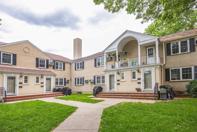 223-36 65th Ave Unit 2A, Bayside, NY 11364 - back of house featuring a balcony, brick siding, a lawn, and a chimney