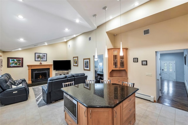 18 Commander Vic Ln, Nesconset, NY 11767 - kitchen featuring stainless steel microwave, a baseboard radiator, light tile patterned flooring, dark stone counters, and a kitchen island