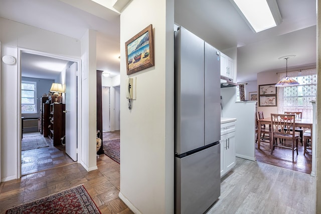 315 W 232nd St Unit 3C, Bronx, NY 10463 - kitchen featuring freestanding refrigerator, white cabinets, under cabinet range hood, decorative light fixtures, and light countertops