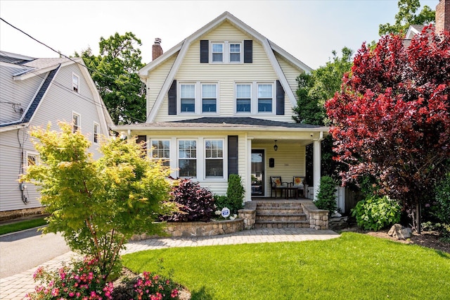 344 N Forest Ave, Rockville Centre, NY 11570 - colonial inspired home featuring a gambrel roof, covered porch, a front lawn, and a chimney