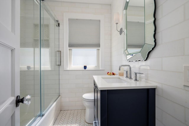 344 N Forest Ave, Rockville Centre, NY 11570 - full bathroom featuring vanity, toilet, combined bath / shower with glass door, and tile walls