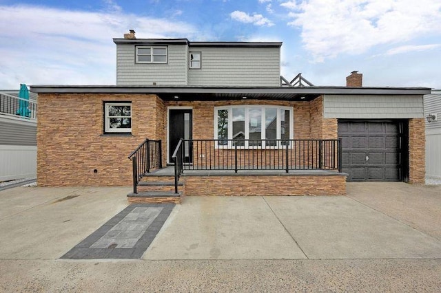 23 Vinton St, Long Beach, NY 11561 - view of front of home with an attached garage, concrete driveway, a chimney, stone siding, and covered porch