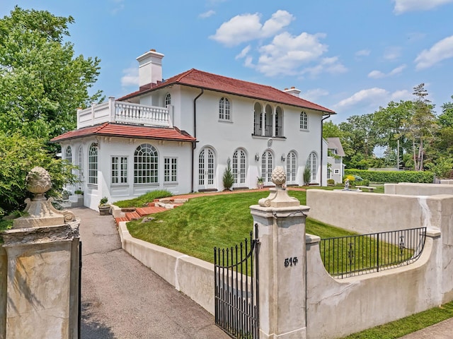 514 Alda Rd, Mamaroneck, NY 10543 - view of front of house featuring french doors, a balcony, a fenced front yard, a chimney, and stucco siding