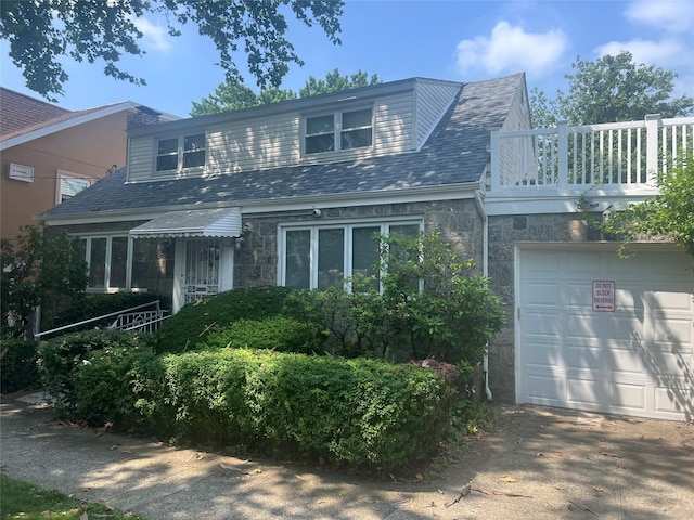 2449 Young Ave, Bronx, NY 10469 - view of front of house featuring stone siding, a balcony, an attached garage, and driveway