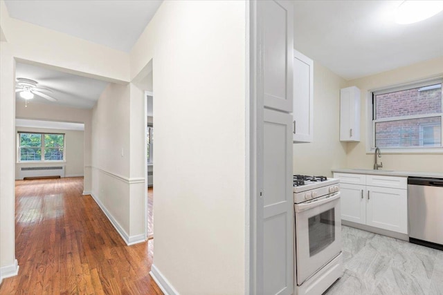 280 Collins Ave Unit 6J, Mount Vernon, NY 10552 - kitchen featuring white range with gas cooktop, dishwasher, radiator, white cabinets, and a sink