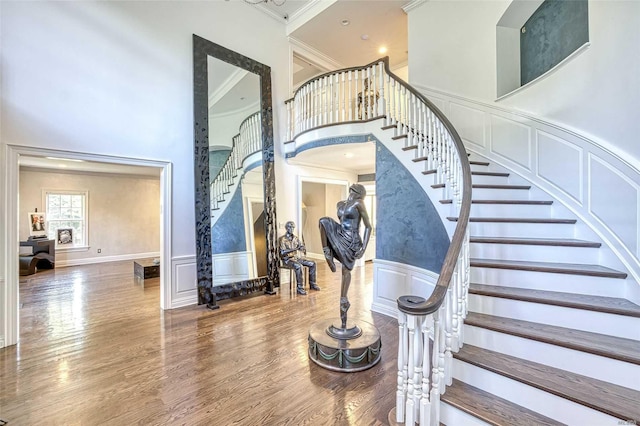 9 Stream Ct, Great Neck, NY 11024 - staircase featuring a towering ceiling, crown molding, wood finished floors, and a wainscoted wall
