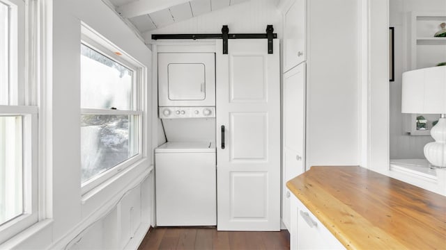 234 Dune Rd, Quogue, NY 11959 - washroom with stacked washer / drying machine, a barn door, and dark wood-type flooring