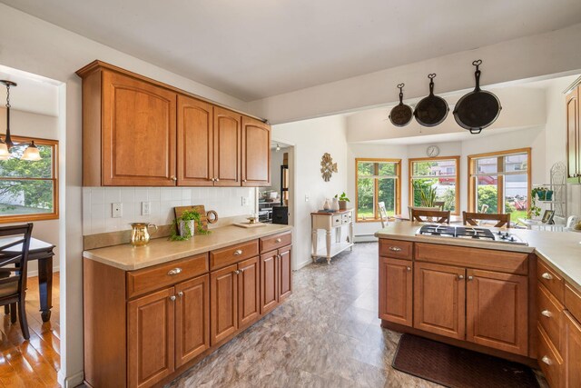 67 Keats Dr, New Windsor, NY 12553 - kitchen with stainless steel gas cooktop, brown cabinetry, light countertops, tasteful backsplash, and baseboards