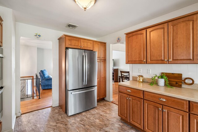 67 Keats Dr, New Windsor, NY 12553 - kitchen with freestanding refrigerator, brown cabinetry, light countertops, and decorative backsplash