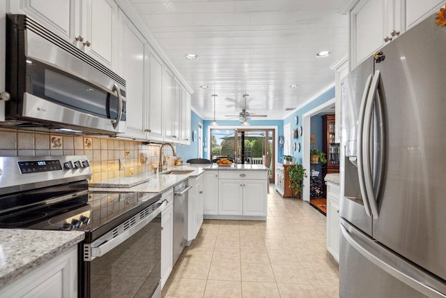 129 Colony Ln, Syosset, NY 11791 - kitchen with appliances with stainless steel finishes, a sink, a peninsula, white cabinetry, and backsplash