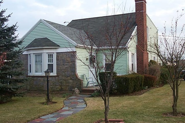 89 S Kensington Ave, Rockville Centre, NY 11570 - view of front of home featuring a chimney, a front lawn, and stone siding