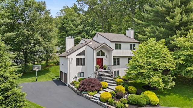 226 Briarwood Dr, Somers, NY 10589 - view of front facade with a chimney, driveway, a garage, stairway, and a front lawn