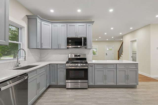 1293 Pulaski Rd, East Northport, NY 11731 - kitchen with gray cabinetry, appliances with stainless steel finishes, a peninsula, a sink, and healthy amount of natural light