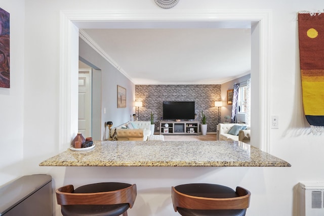 131-2 S Highland Ave Unit A3, Ossining, NY 10562 - kitchen featuring light stone counters, ornamental molding, and a kitchen bar
