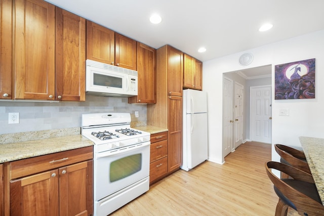 131-2 S Highland Ave Unit A3, Ossining, NY 10562 - kitchen with white appliances, brown cabinetry, ornamental molding, light wood-style floors, and light stone countertops