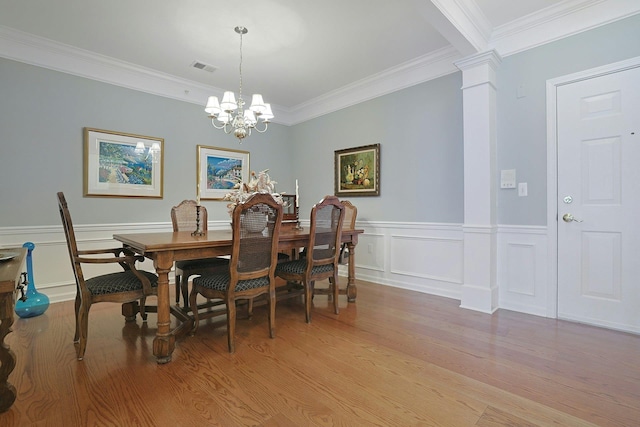 24 N De Baun Ave Unit 308, Suffern, NY 10901 - dining area featuring a chandelier, light wood-type flooring, crown molding, a wainscoted wall, and ornate columns