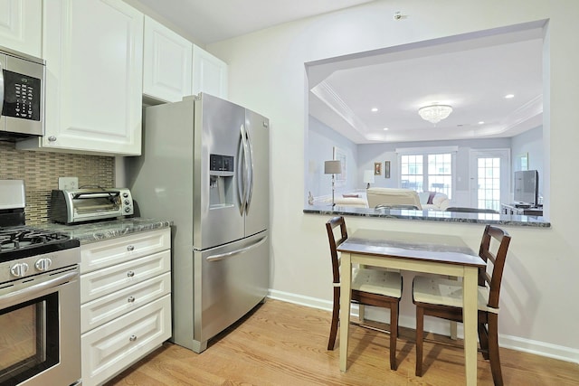 24 N De Baun Ave Unit 308, Suffern, NY 10901 - kitchen featuring stainless steel appliances, light wood-type flooring, a tray ceiling, tasteful backsplash, and white cabinetry