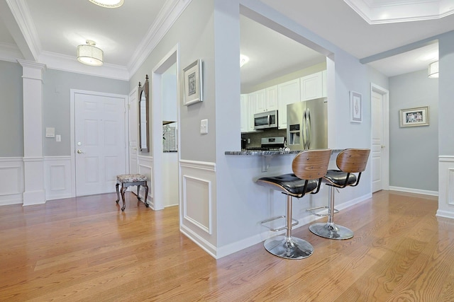 24 N De Baun Ave Unit 308, Suffern, NY 10901 - kitchen featuring appliances with stainless steel finishes, a kitchen breakfast bar, light wood finished floors, white cabinets, and crown molding