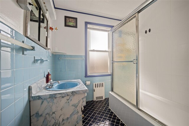 4614 Carpenter Ave, Bronx, NY 10470 - bathroom with radiator heating unit, tile patterned floors, bath / shower combo with glass door, vanity, and tile walls