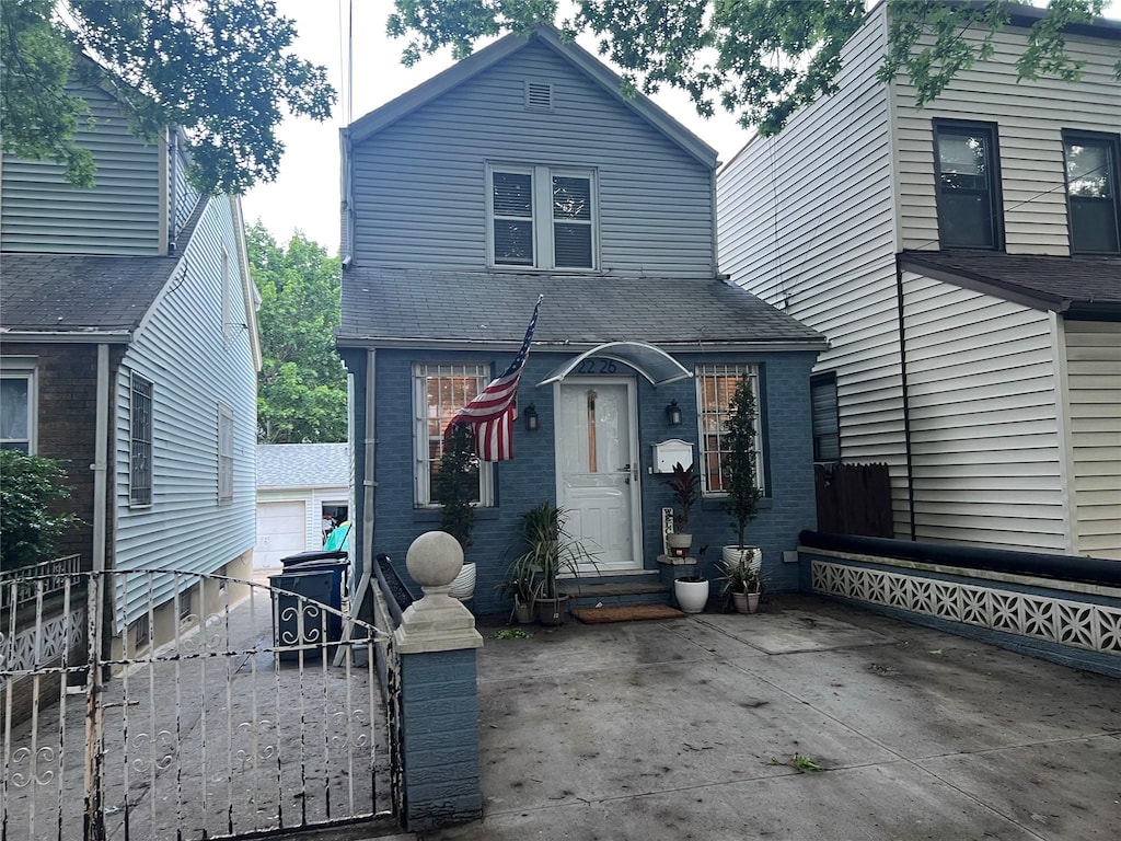22-26 74th St, East Elmhurst, NY 11370 - view of front of home featuring brick siding, a gate, a shingled roof, and an outdoor structure