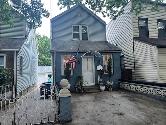 22-26 74th St, East Elmhurst, NY 11370 - view of front of home featuring brick siding, a gate, a shingled roof, and an outdoor structure