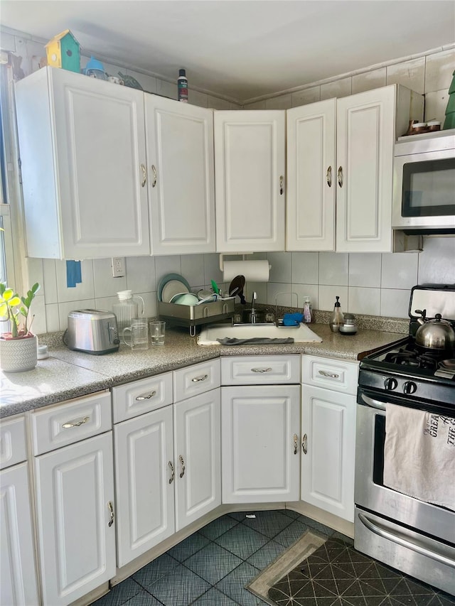 22-26 74th St, East Elmhurst, NY 11370 - kitchen featuring stainless steel appliances, white cabinetry, backsplash, and light countertops